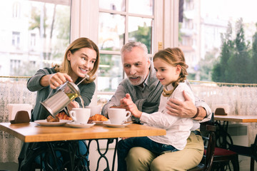 Breakfast in cafeteria. Happy grandparents and cute little girl feeling memorable while having breakfast in cafeteria