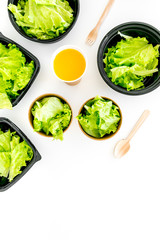 Food delivery concept. Healthy food. Diet meal with lettuce in plastic boxes, green tea, disposable tableware on white background top view copy space