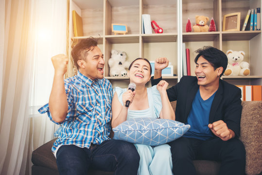 Group Of Friends Having Fun At Living Room Singing A Song Together