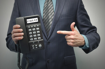 Telephone in the businessman hand isolated on the gray background. Call us.