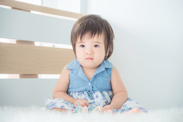 Little asian cute girl sitting on bed in bedroom