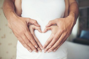 Pregnant Woman and Her Husband hand showing heart shape.