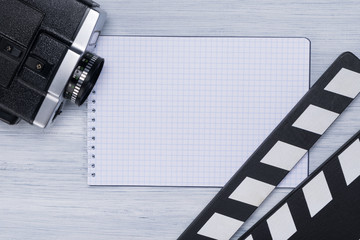 Clapperboard, camcorder and notebook for records are on the light background of the director's table