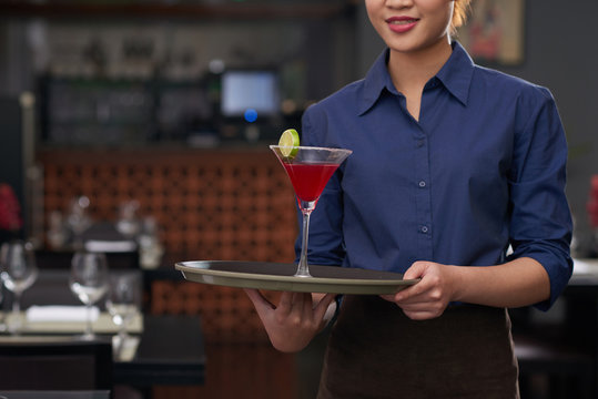 Cropped image of waitress holding tray with cocktail on it