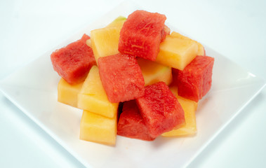 Fresh watermelons and melons on a white plate