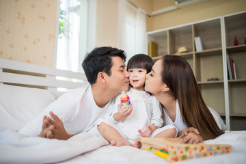 Obraz premium Happy child with parents playing in the bed at home