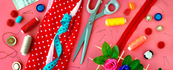 Items for sewing in the form of a panorama. Sewing clothes. Measuring tape, tailoring scissors, threads, buttons, needles, fabric on a pink background in the form of a panorama.