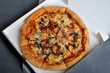 spicy pizza with sausages in a box