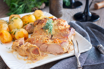 Baked turkey thigh meat with potatoes on a white dish, horizontal