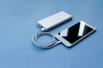 Smartphone Charging with Power Bank on Blue Background