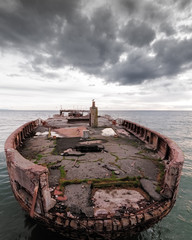 decrepit ship on ocean with cloudy sky