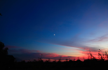 Beautiful sunset. Blurred shot of the dramatic sunset on steppe. Red clouds as a defocused natural background.Young moon in the evening