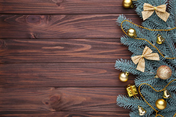 Christmas decoration. Fir-tree branch with gold balls, little gifts and bows on a brown background