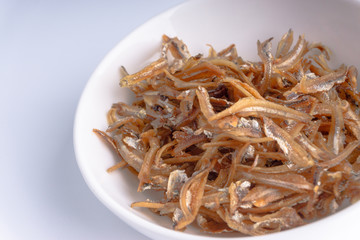 Fried anchovies on white background with selective focus and crop fragment