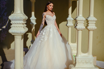 Fototapeta premium Happy bride before wedding. Beautiful wedding dresses in boutique. Wonderful bridal gown. woman is preparing for wedding. Elegant wedding salon is waiting for bride. Feeling grateful