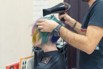 Naklejka premium A woman is done coloring her head in blue at the hairdresser’s salon. Change the image of a woman.