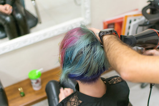 A woman is done coloring her head in blue at the hairdresser’s salon. Change the image of a woman.