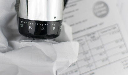 The concept of deadline. Mechanical timer at zero against the background of scattered documents.