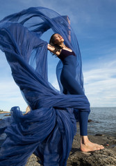 Woman dancing with blue fabric on the beach in Connecticut.