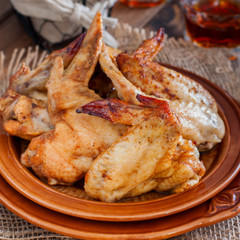 Baked chicken wings on a wooden table, square