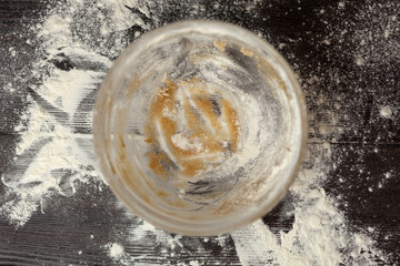 Soiled bowl after cooking dough for Christmas cookies with cinnamon, ginger and sugar. On a dark brown background sprinkle with flour. New year's magic. With the blur