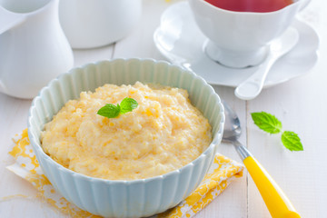 Milk corn porridge in a blue bowl, horizontal