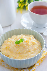 Milk corn porridge in a blue bowl for breakfast, selective focus