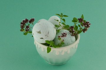 bath bombs with oregano extract.green bath bombs and sprigs of fresh oregano in a green round cup...