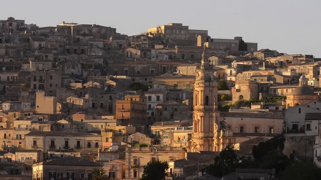  Modica in the Sicily - Italy with the landscape highlighted in church. Birds fly from side to side. Sunlight in some houses.