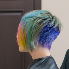 Naklejka premium Woman 30-40 smiles and made coloring of hair in different colors in a hairdressing salon. Change the image of a woman.