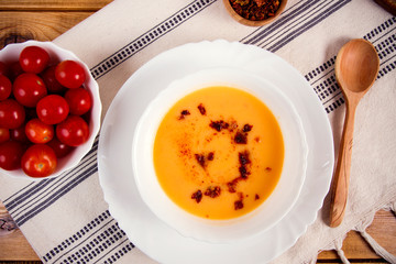 Tomato soup in a white plate on a wooden background