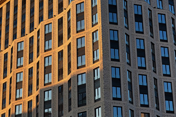 Brick wall of a skyscraper with windows. Left illuminated by sunset, right in the shade