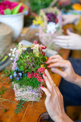 Female hands making beautiful bouquet of flowers on background
