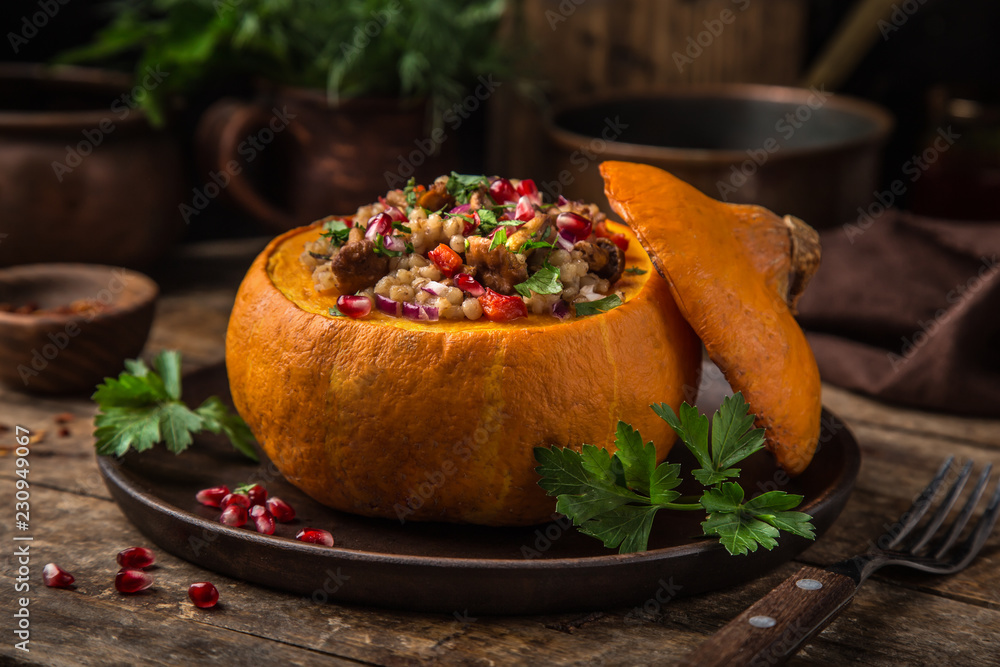 Sticker whole pumpkin stuffed with barley and vegetables, served with pomegranate and parsley