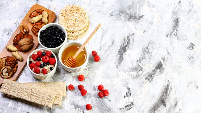 Healthy and tasty breakfast with crispybread, berries, honey and nuts, on a light background. Flat lay. copy space. Authentic lifestyle image