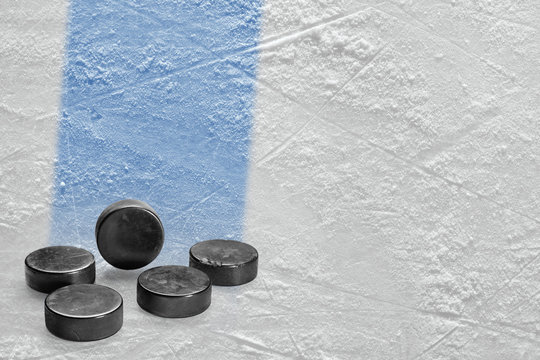 Pucks and fragment of the ice arena with a blue line
