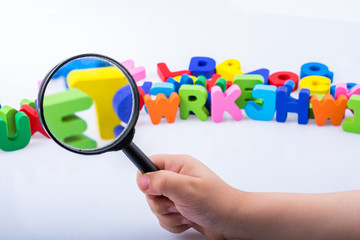 Hand holding magnifying glass over alphabet letter cubes