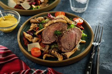 Salad with warm beef with oyster mushrooms, tomatoes and greens.