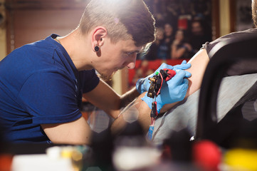 Tattoo artist creating a tattoo on a man's arm.