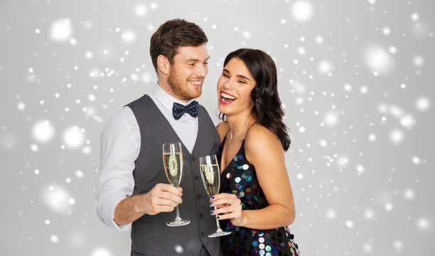 Christmas Party, New Year Celebration And Holidays Concept - Happy Couple With Glasses Drinking Non Alcoholic Champagne Over Grey Background And Snow