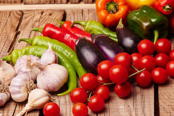 Cherry tomatoes, peppers, garlic, eggplants on a wooden table. Fresh organic vegetables..