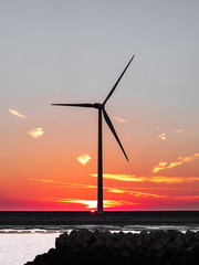 Silhouette of wind turbine with sun setting in background