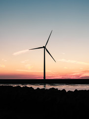 Sunset with silhouette of wind turbine in foreground