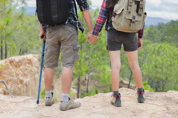 Couple of hikers with backpacks looking over mountains view. Hiking and leisure theme