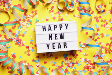 happy new year party celebration flat lay with confetti and streamers on yellow background
