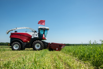 Naklejka premium heavy powerful red harvester in the field during the demonstration
