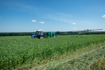 blue tractor in the field is preparing for chemical treatment of plants