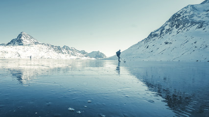 Beautiful view of the winter lake in the mountains. Clearing ice and winter mood, ice hockey player...