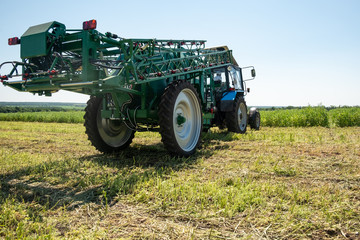 Fototapeta premium blue tractor in the field is preparing for chemical treatment of plants