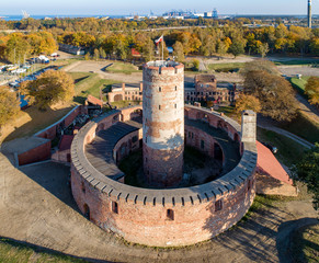 Medieval Wisloujscie Fortress with old lighthouse tower in port of Gdansk, Poland. A unique monument of the fortification works. Aerial view at sunset. Exterior Northern  Gdansk port in the background